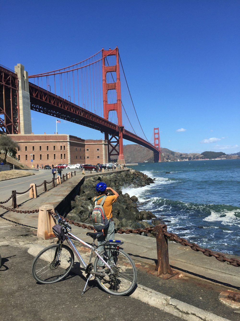 昼間、橋の上を自転車で走る黄色いシャツを着た男性
