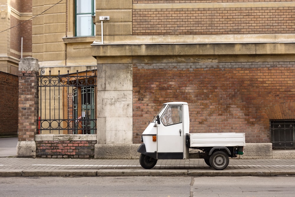 white car parked beside brown brick wall