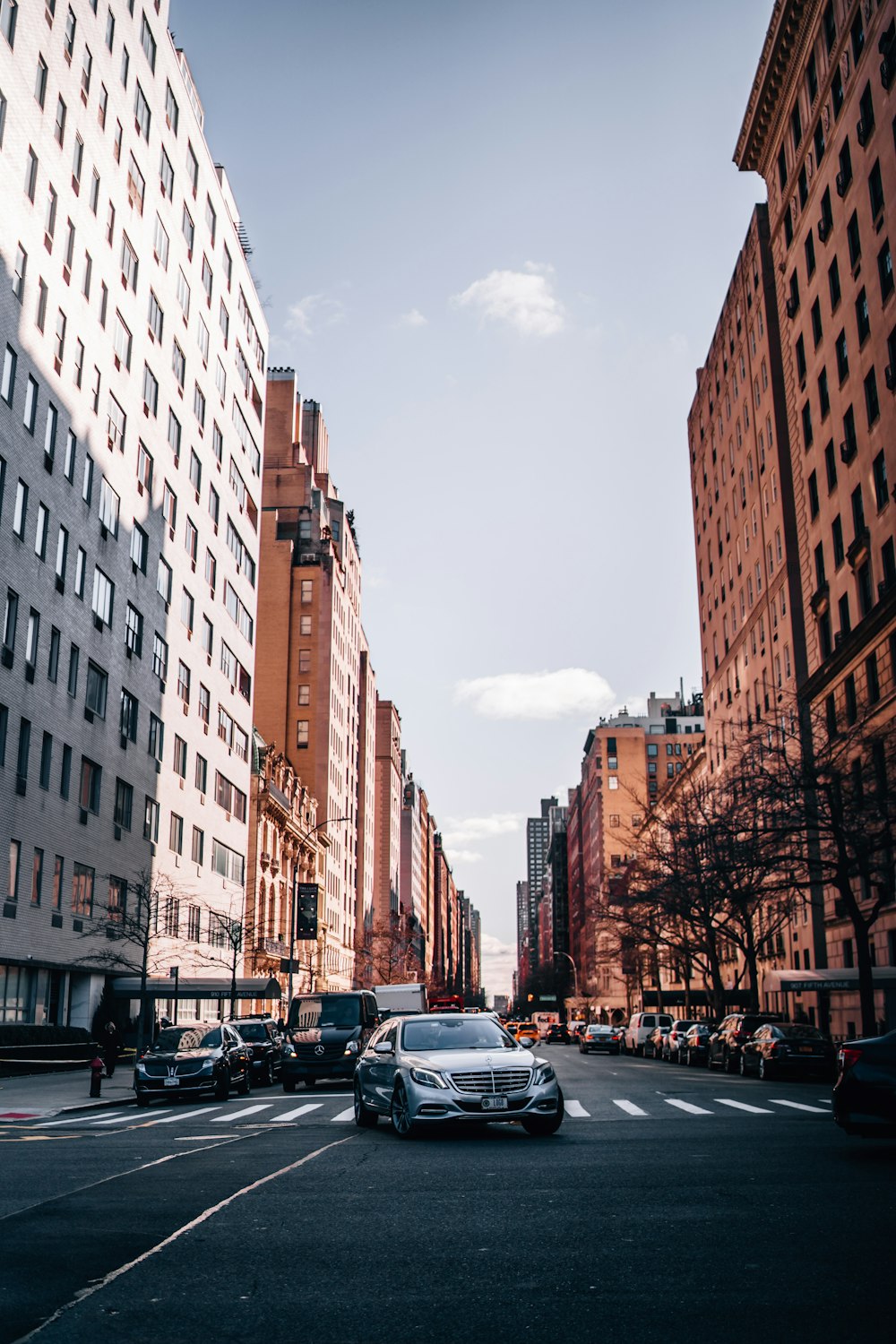 cars on road between high rise buildings during daytime