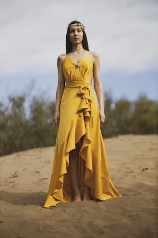 woman in yellow tube dress standing on brown sand during daytime