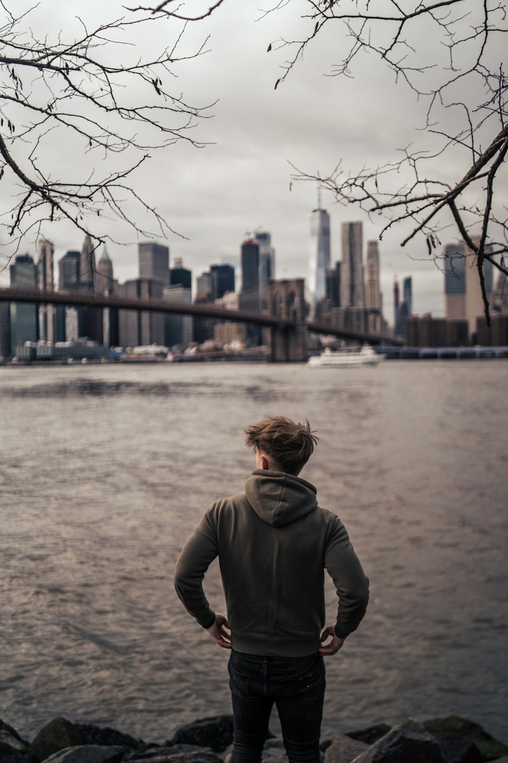 woman in gray hoodie standing near body of water during daytime