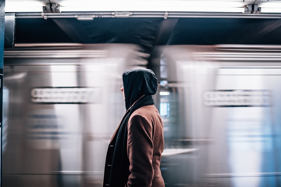 man in brown hoodie standing in front of train, New York Subway