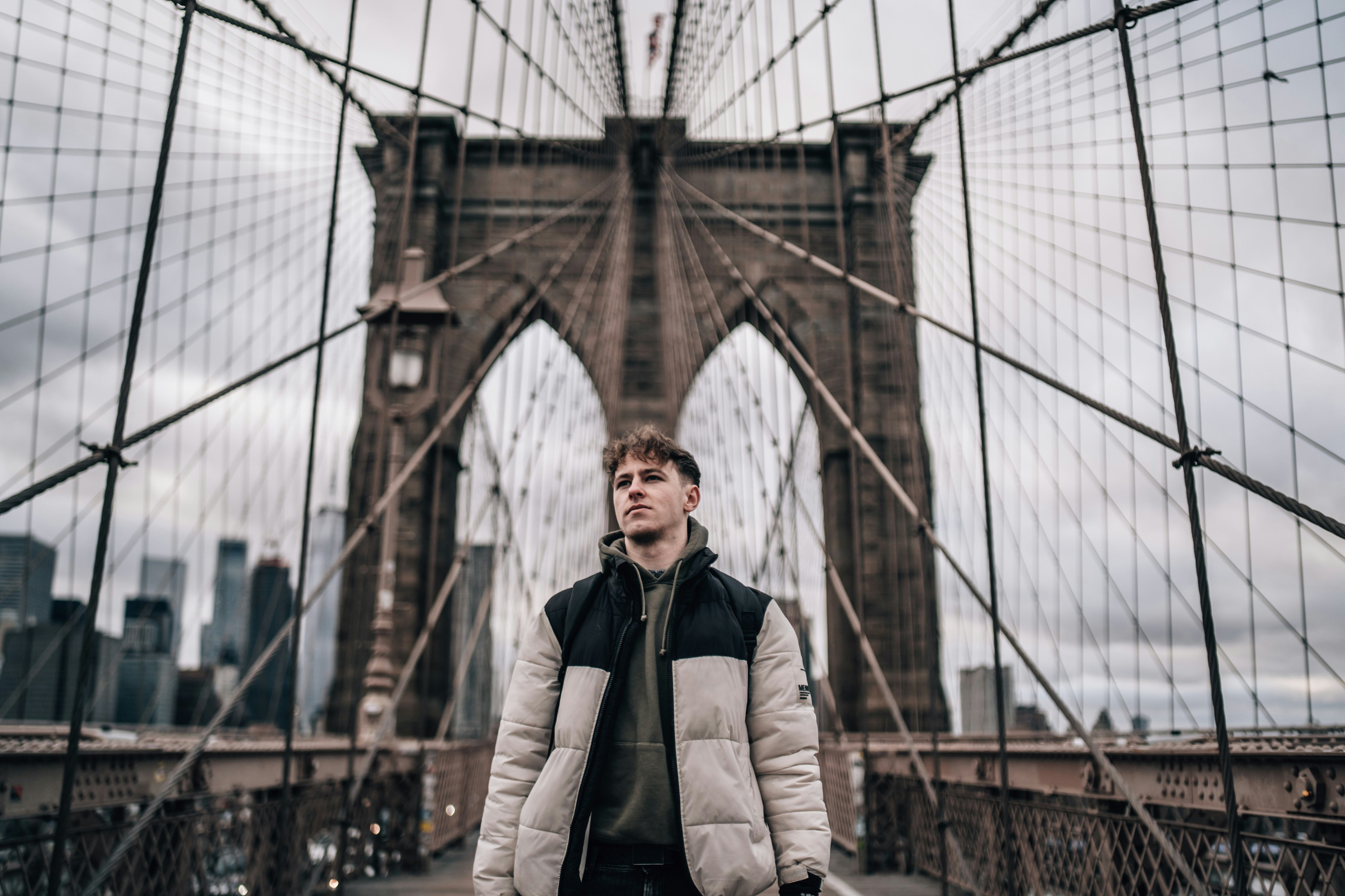 man in brown coat standing on bridge during daytime