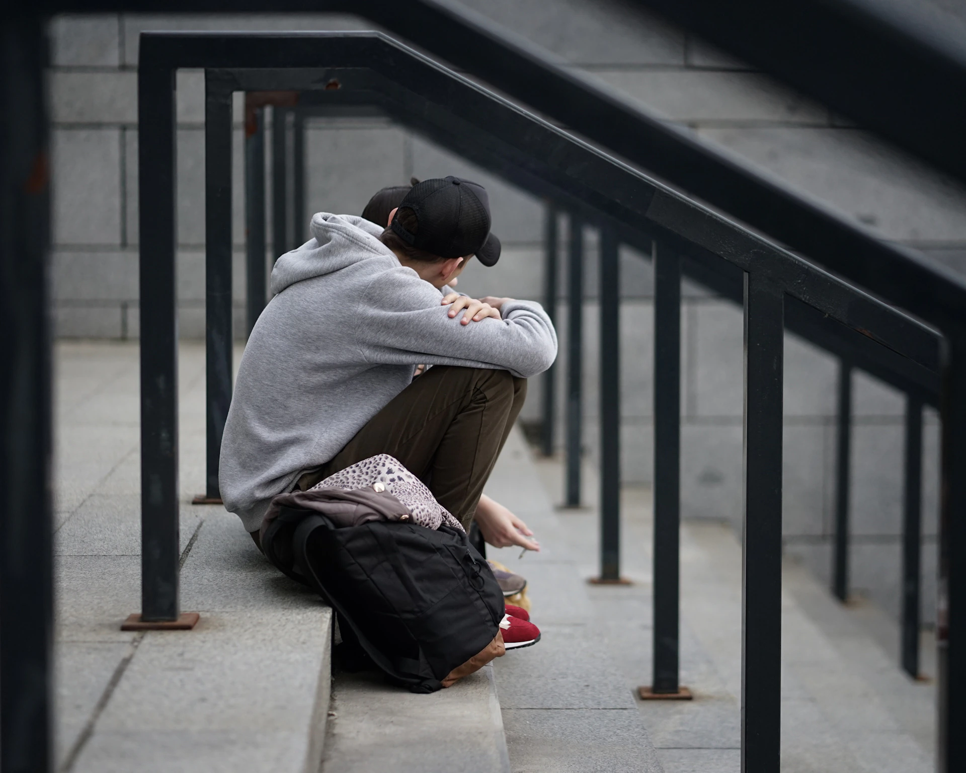 man in gray long sleeve shirt and black pants sitting on gray concrete bench during daytime