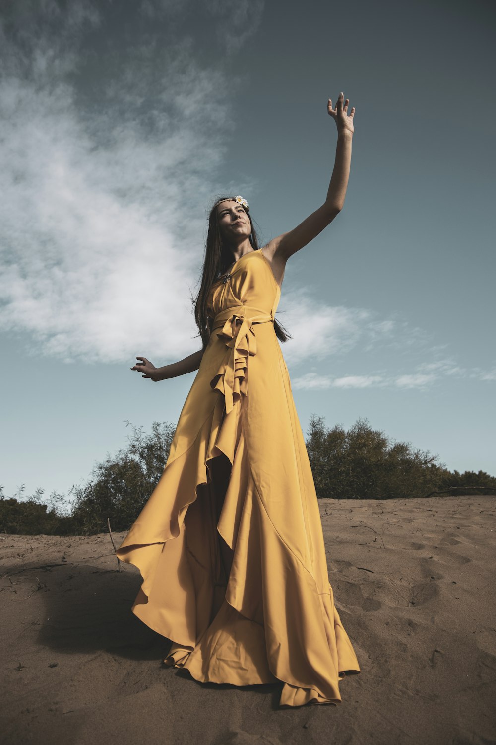 mulher no vestido amarelo sem mangas em pé na areia marrom durante o dia