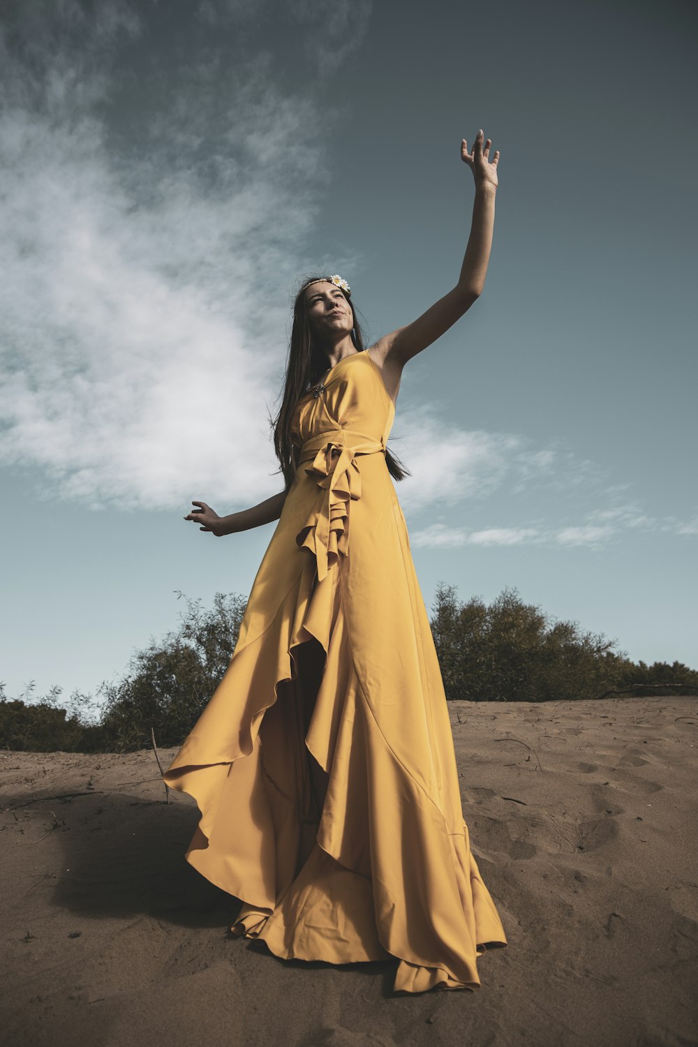 Frau in gelbem ärmellosem Kleid, die tagsüber auf braunem Sand steht