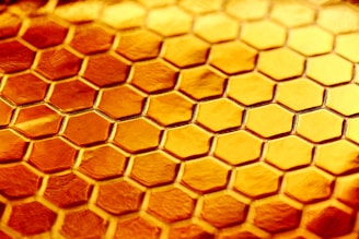 A modern hexagonal pattern background with subtle honeycomb shapes in warm yellow and gray tones.