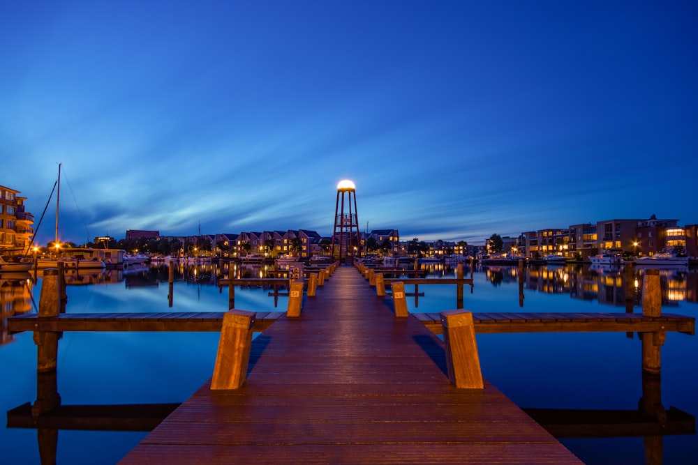 Muelle de madera marrón en el cuerpo de agua durante la noche