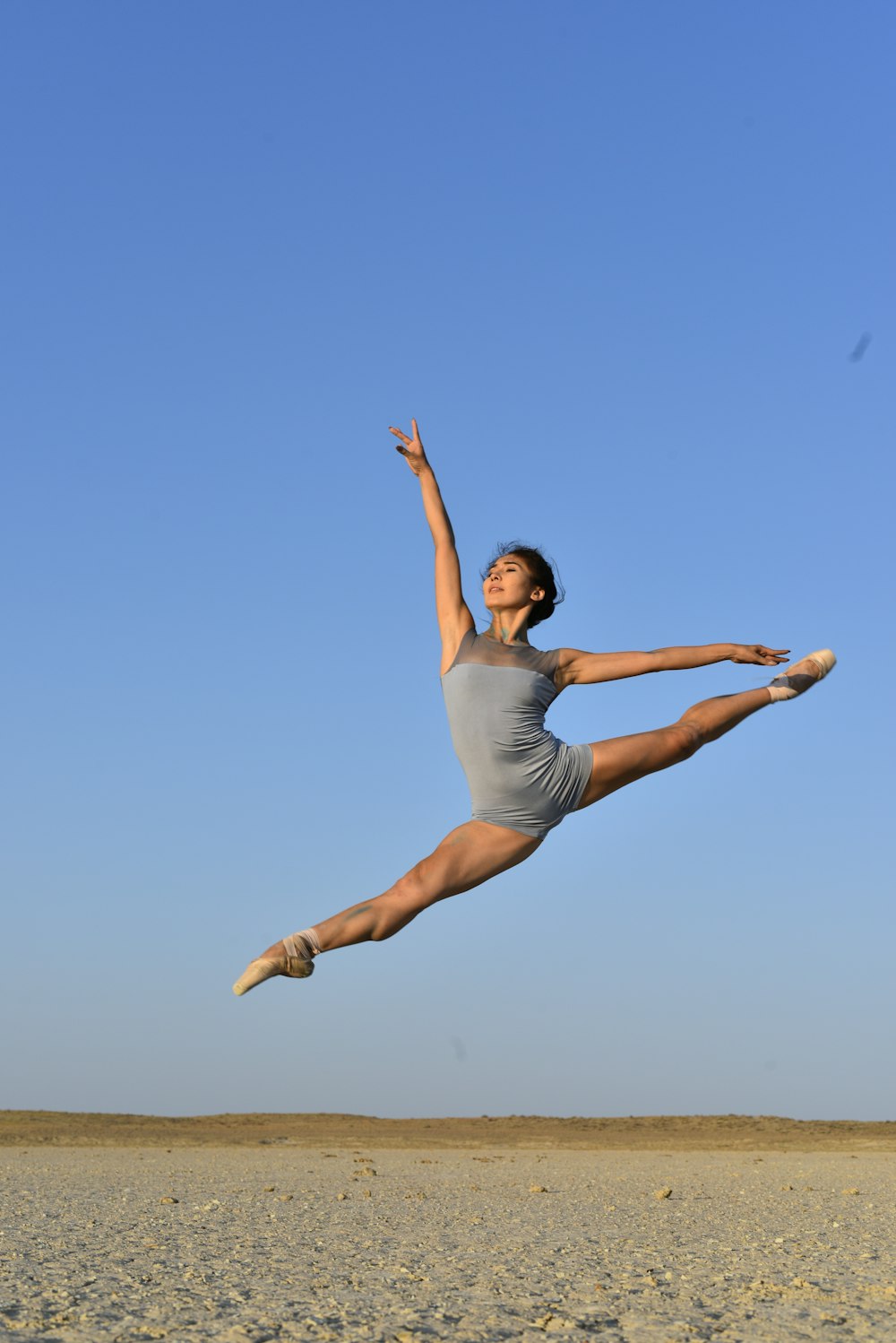 woman in white tank top and blue denim jeans jumping under blue sky during daytime