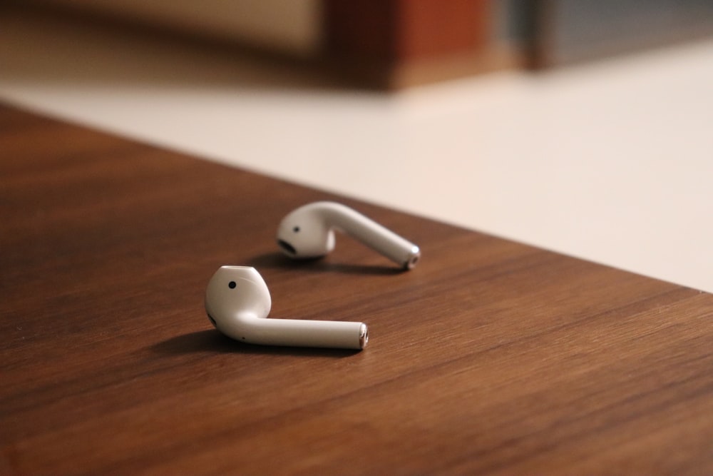 white apple earpods on brown wooden table