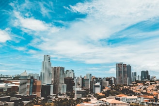city buildings under blue sky and white clouds during daytime