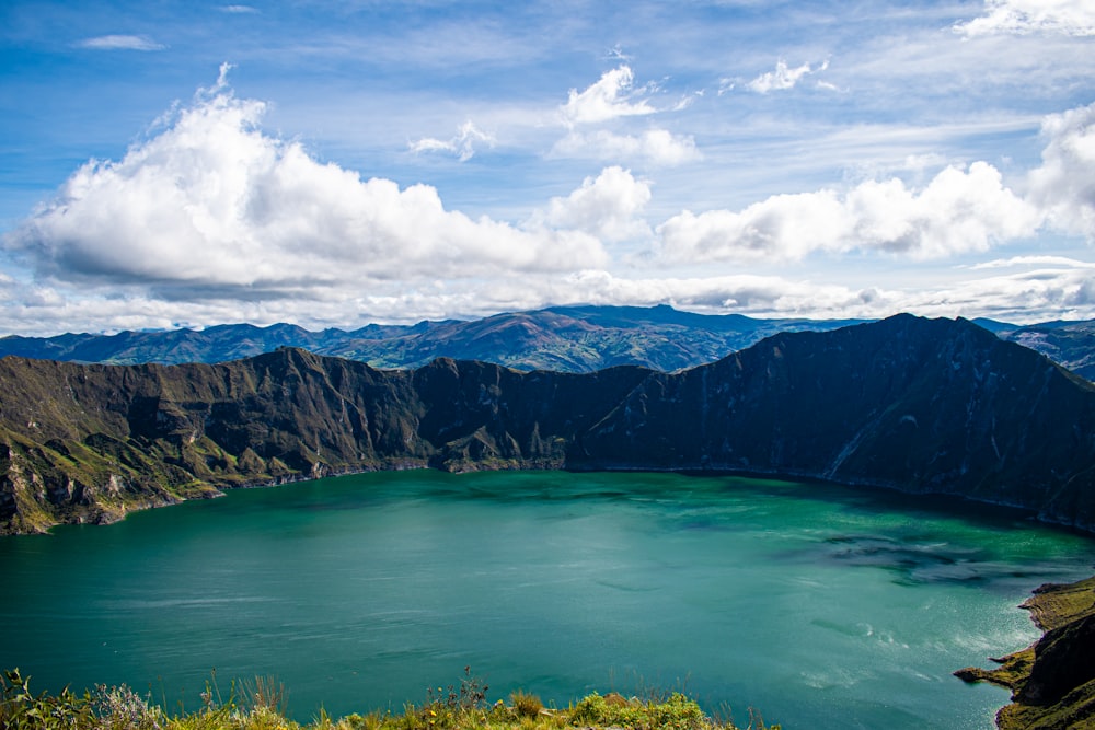 lago verde perto da montanha sob o céu azul durante o dia