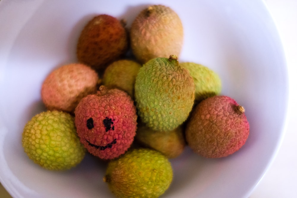 green and brown fruits on white ceramic bowl