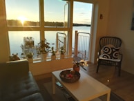 A cozy living room with large windows overlooking a serene waterfront, showcasing Barbee Homes’ signature style.