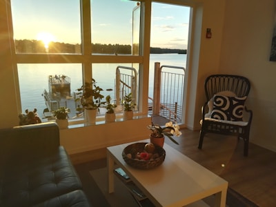 Sunlit living room with large windows and lake views, decorated in warm tones.