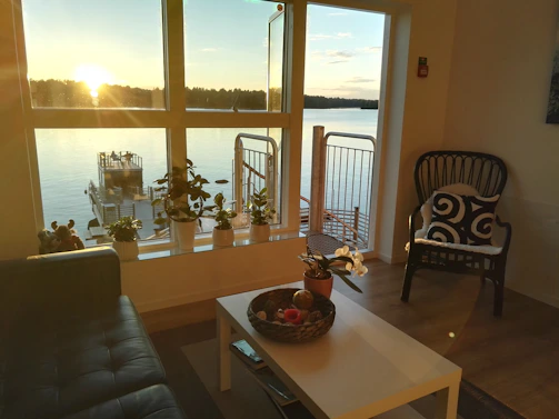 Sunlit living room of a modern condo with floor-to-ceiling windows overlooking Lake Oswego.