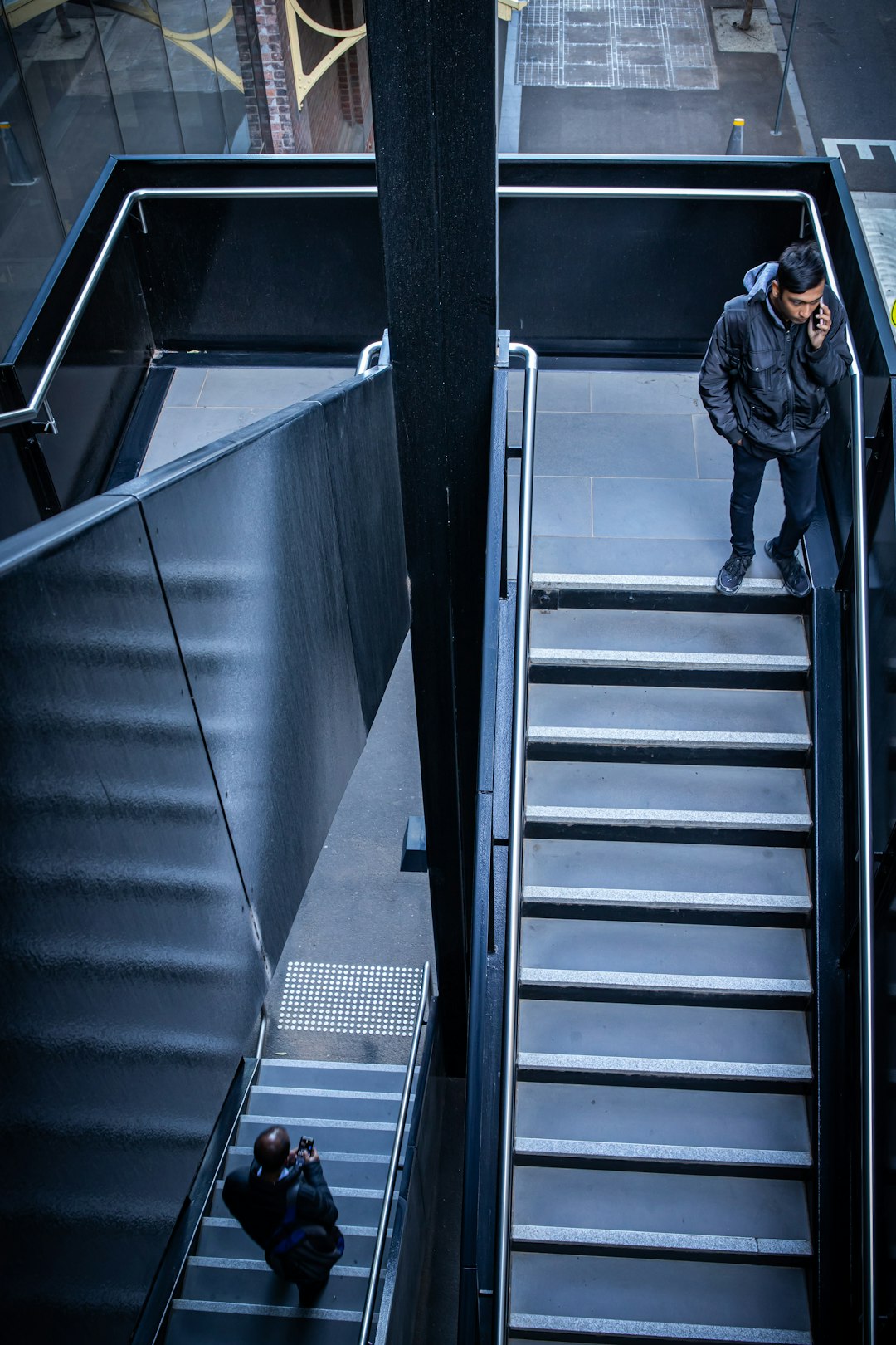 woman in black jacket walking on gray staircase