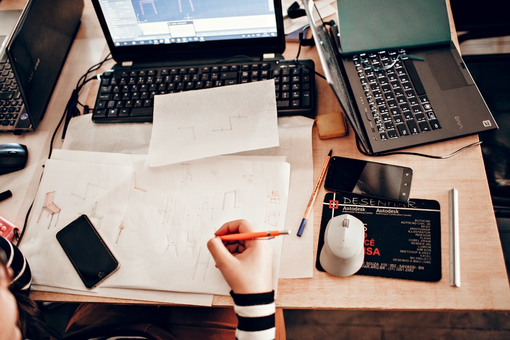 person holding white printer paper near black laptop computer