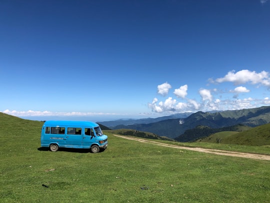 blue van on green grass field during daytime in Borjomi-Kharagauli National Park Georgia