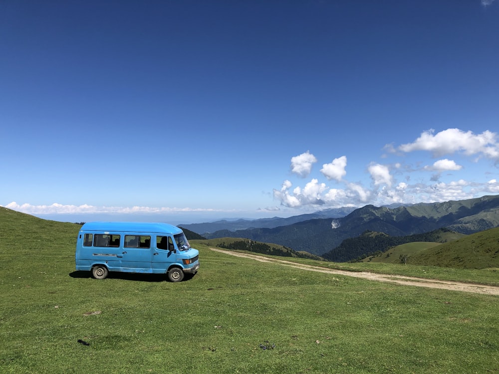 blue van on green grass field during daytime