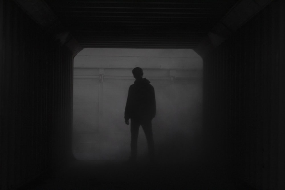 silhouette of man standing in front of window