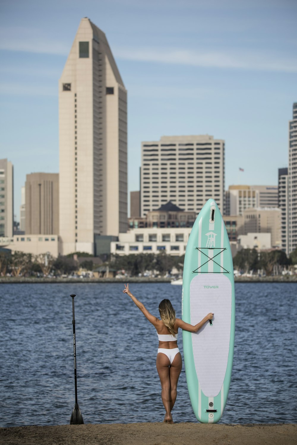 woman in white bikini sitting on surfboard during daytime
