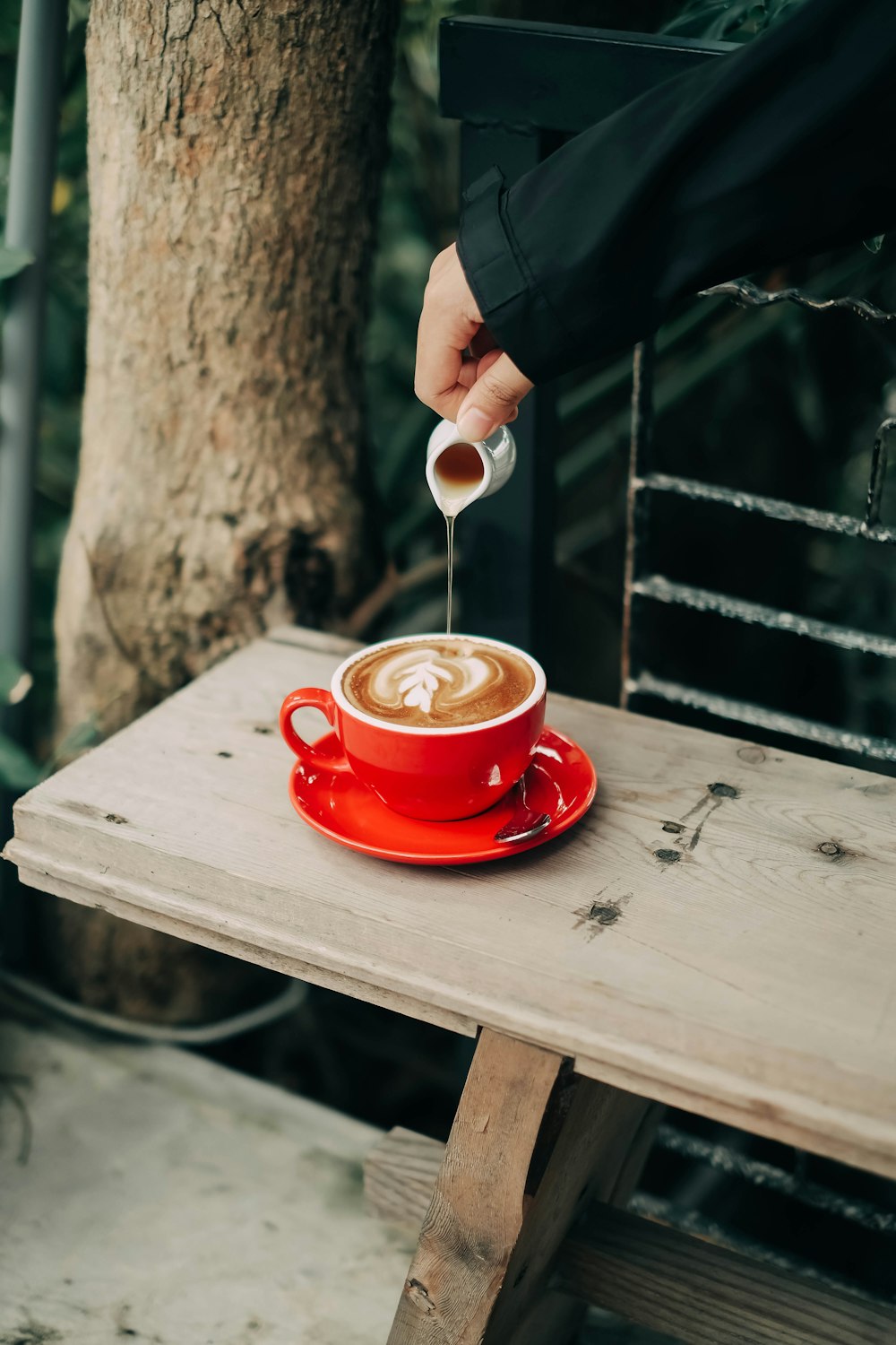 person holding red ceramic mug with spoon