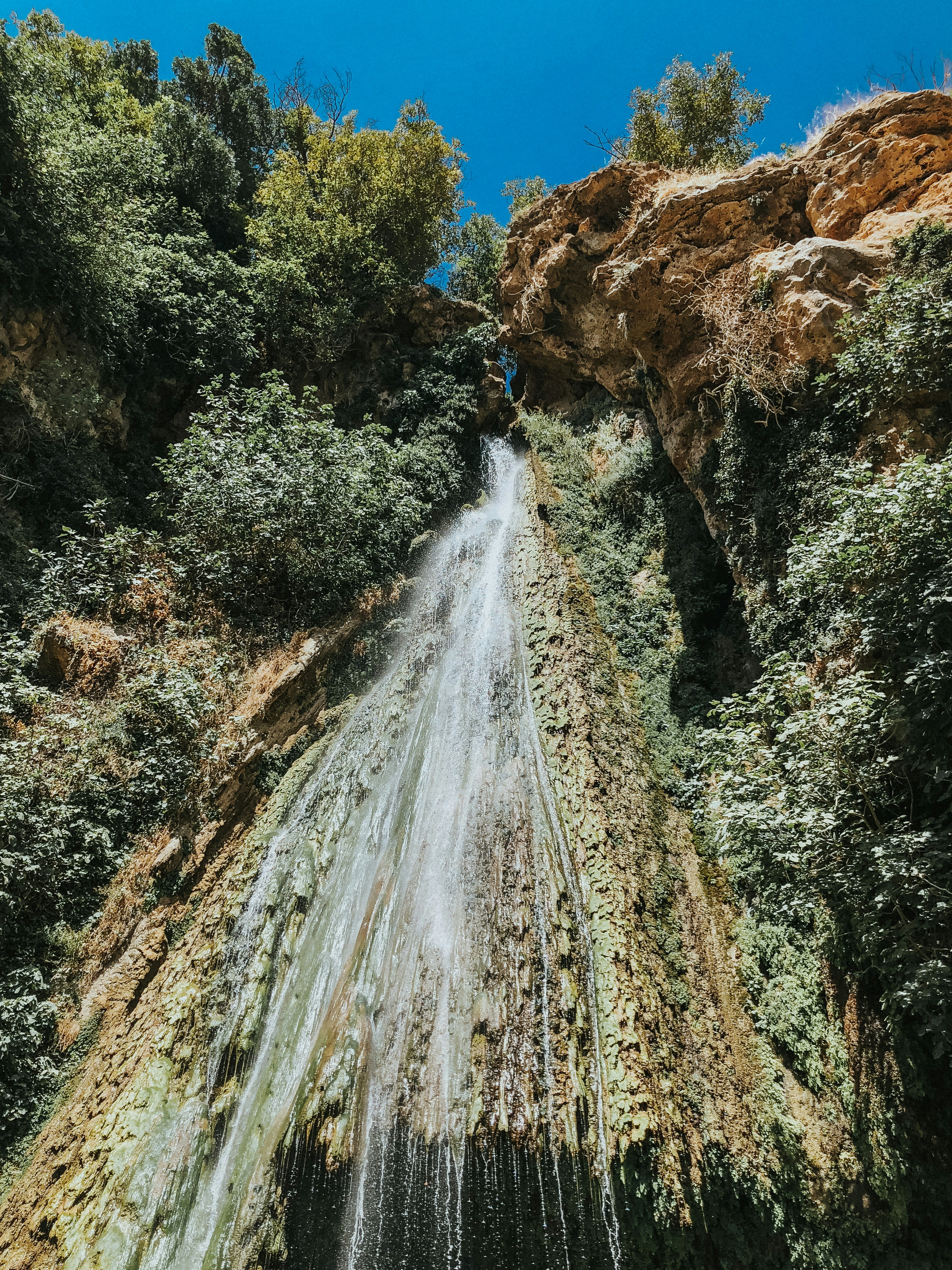water falls on brown rocky mountain during daytime