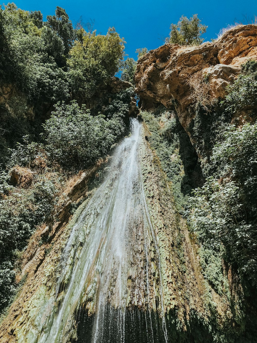 water falls on brown rocky mountain during daytime