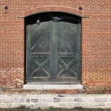 black wooden door on brown brick wall