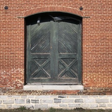 black wooden door on brown brick wall