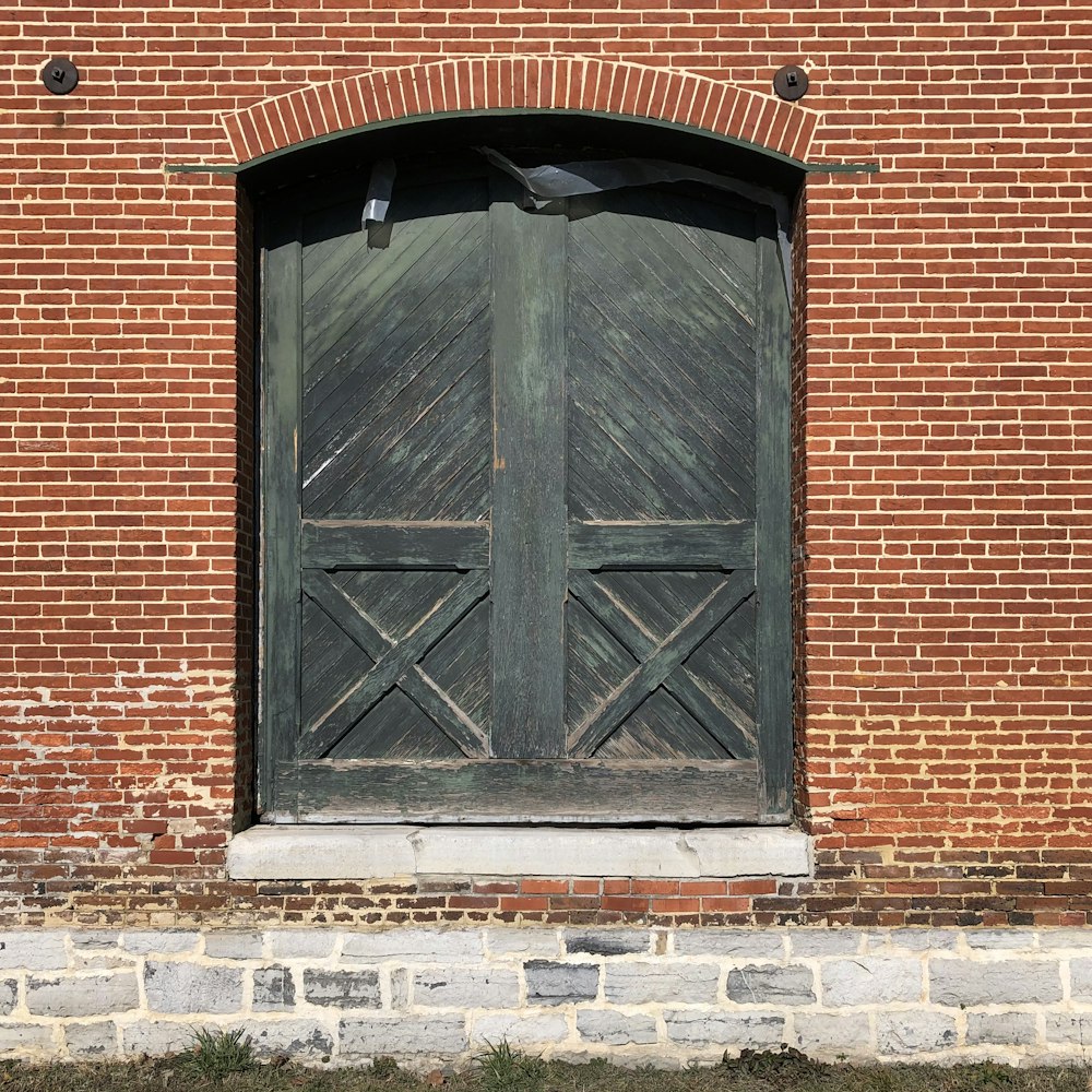 black wooden door on brown brick wall