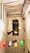 A narrow space with exposed brick walls features a creative installation depicting silhouettes of flying children and objects on the wall. Colorful lamps at different heights add a whimsical element, casting vibrant red, green, and yellow light against the neutral backdrop.