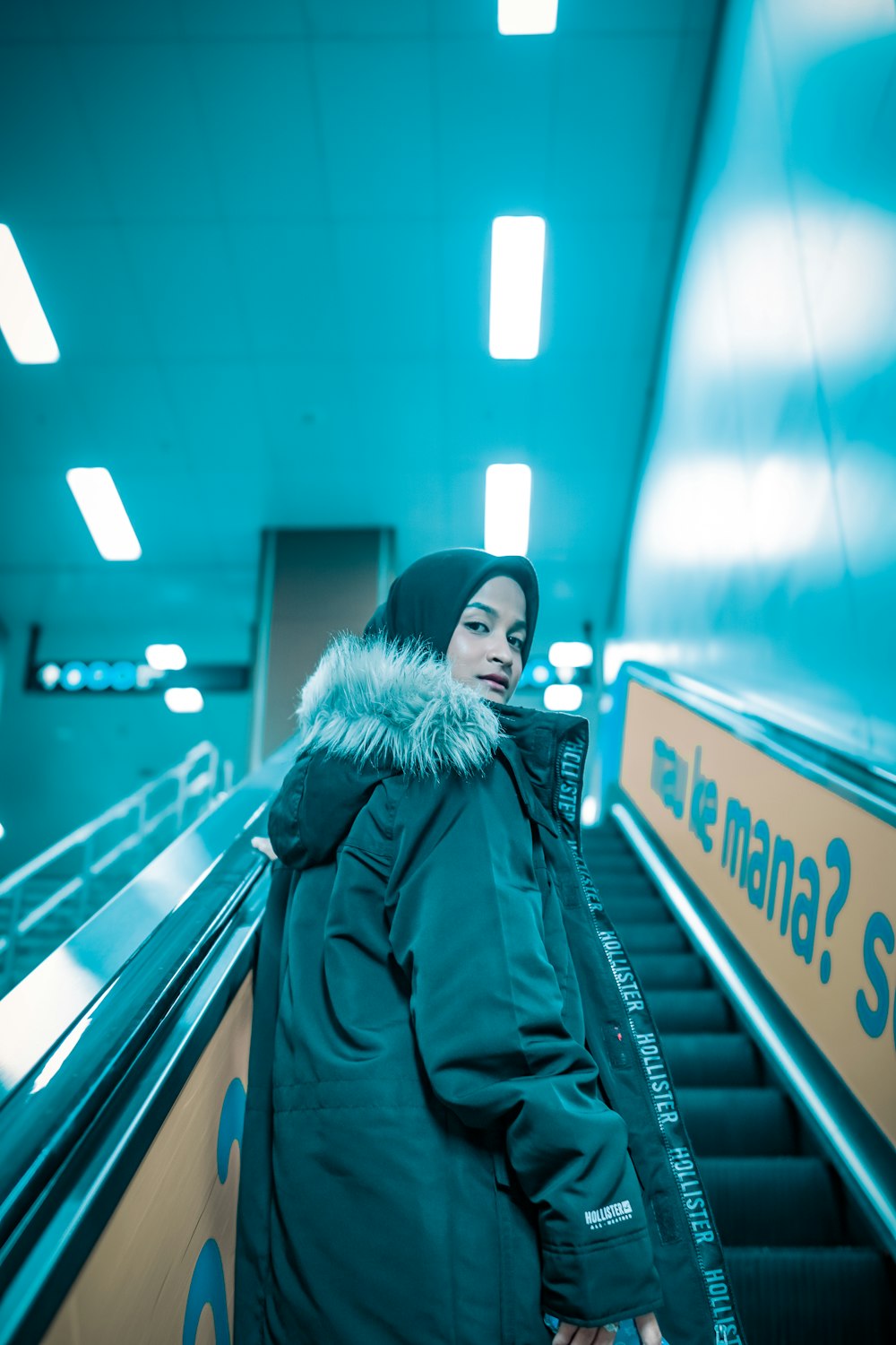 woman in black and white parka jacket standing on escalator
