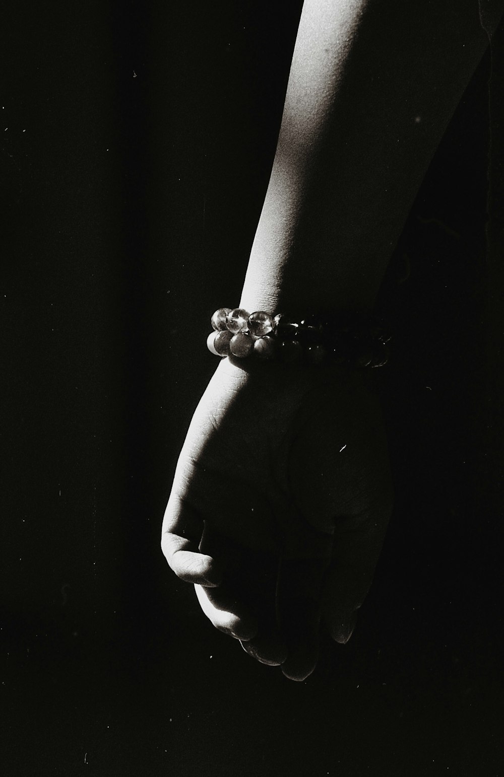 grayscale photo of person wearing beaded bracelet