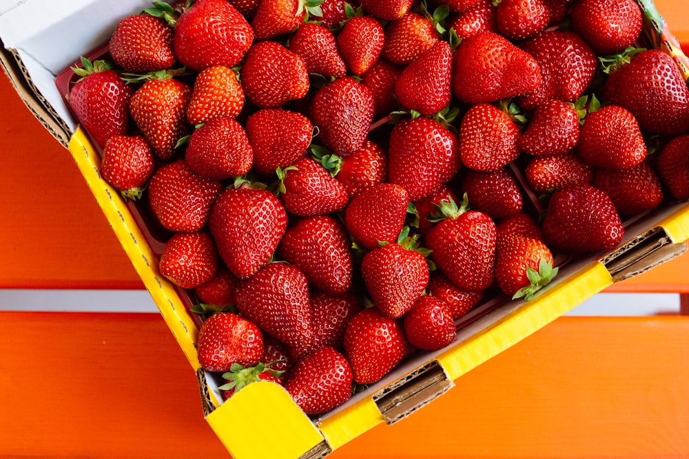 red strawberries on yellow plastic container