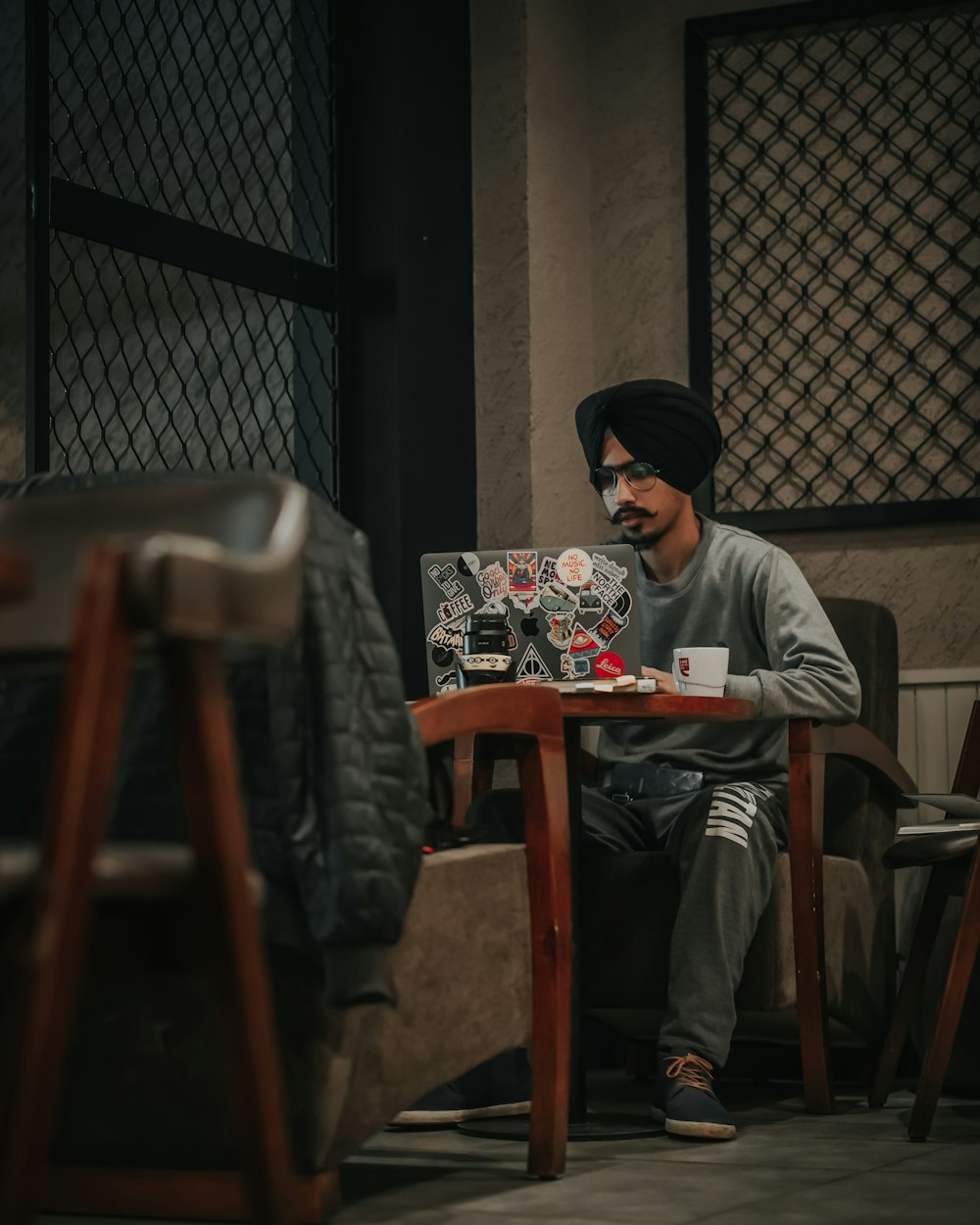 man in gray sweater sitting on brown wooden chair