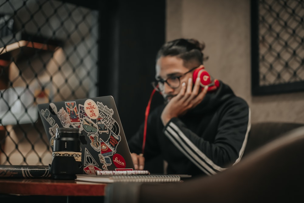 um homem sentado em uma mesa com um laptop e celular