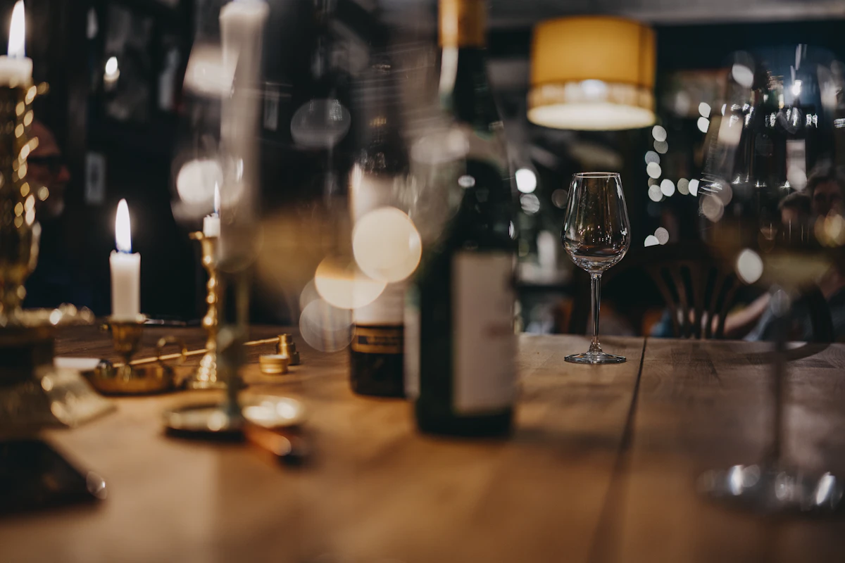 Two glasses of red wine poured on a dark table under low amber light at Maison Noir.