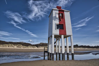 white and red wooden lifeguard house on beach shore during daytime