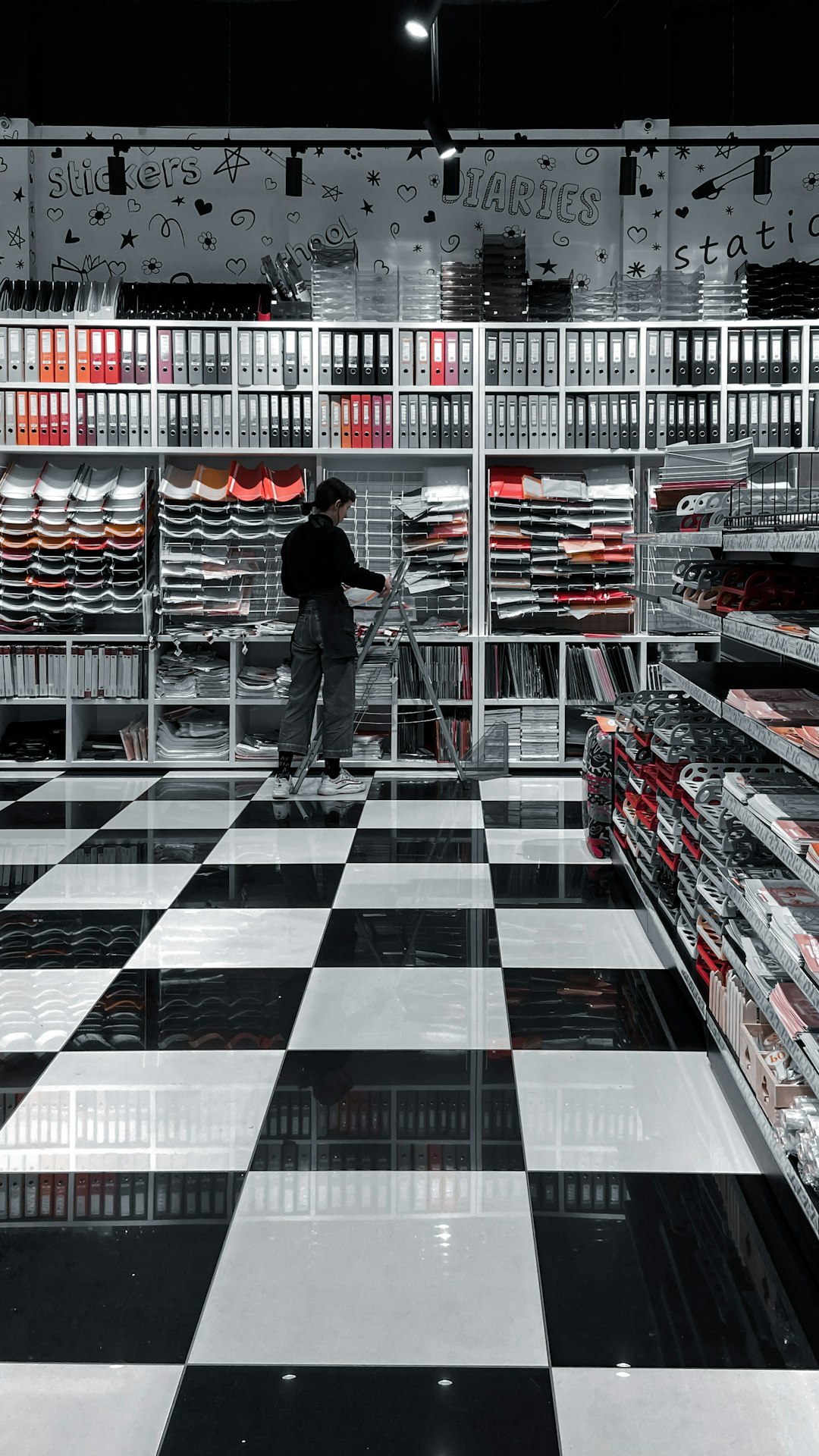 man in black jacket and blue denim jeans standing on black and white checkered floor tiles