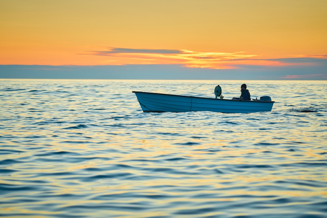 silhouette of 2 people riding on boat during sunset