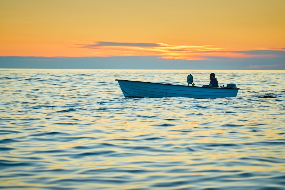 silhouette of 2 people riding on boat during sunset