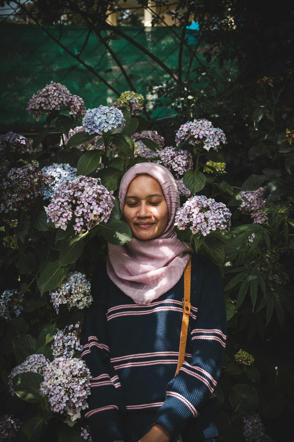 woman in black and white floral hijab standing beside green plant