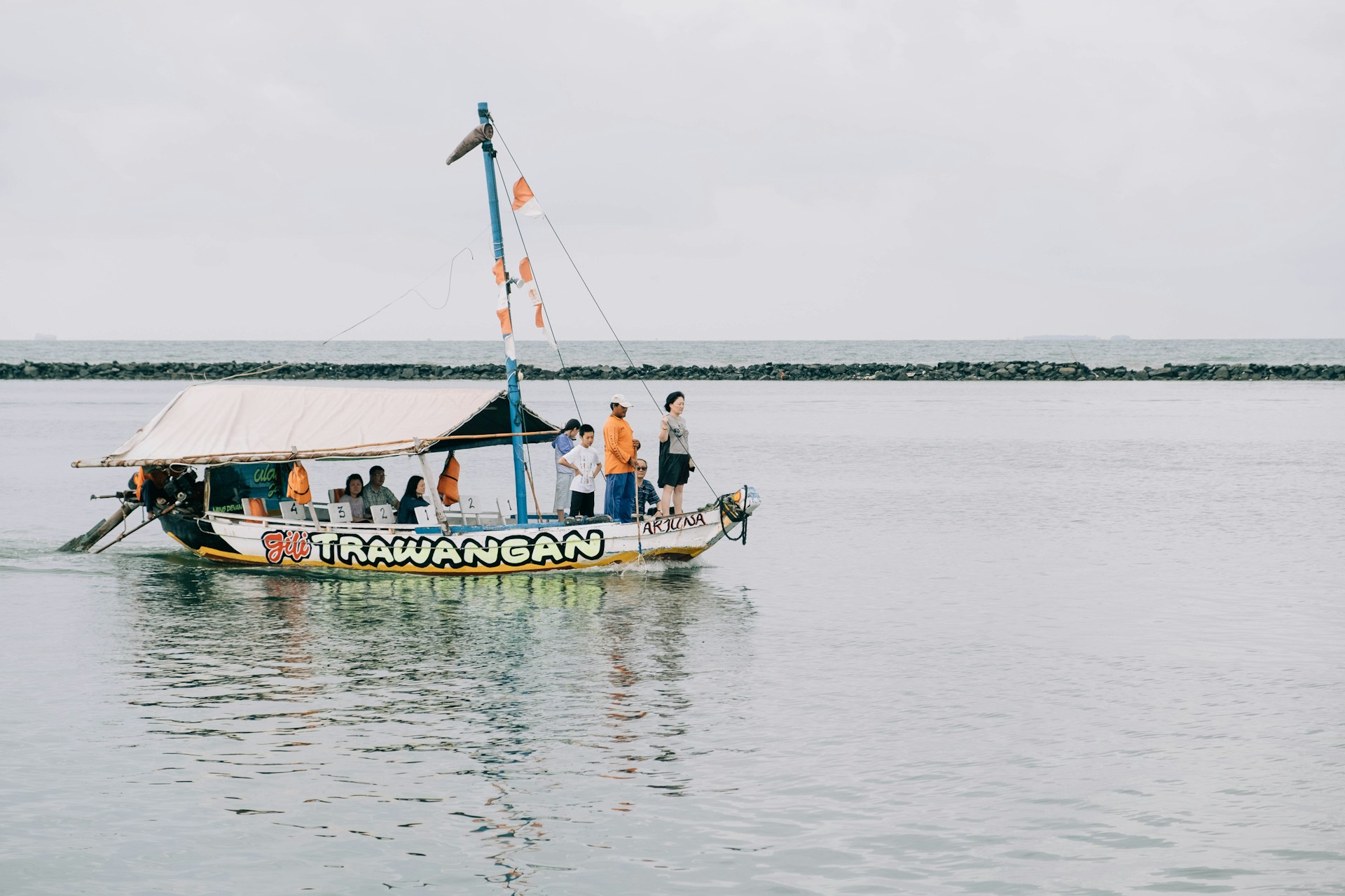 Crystal clear waters and white sandy beaches of Gili Terawangan with traditional boats docked on the shore.
