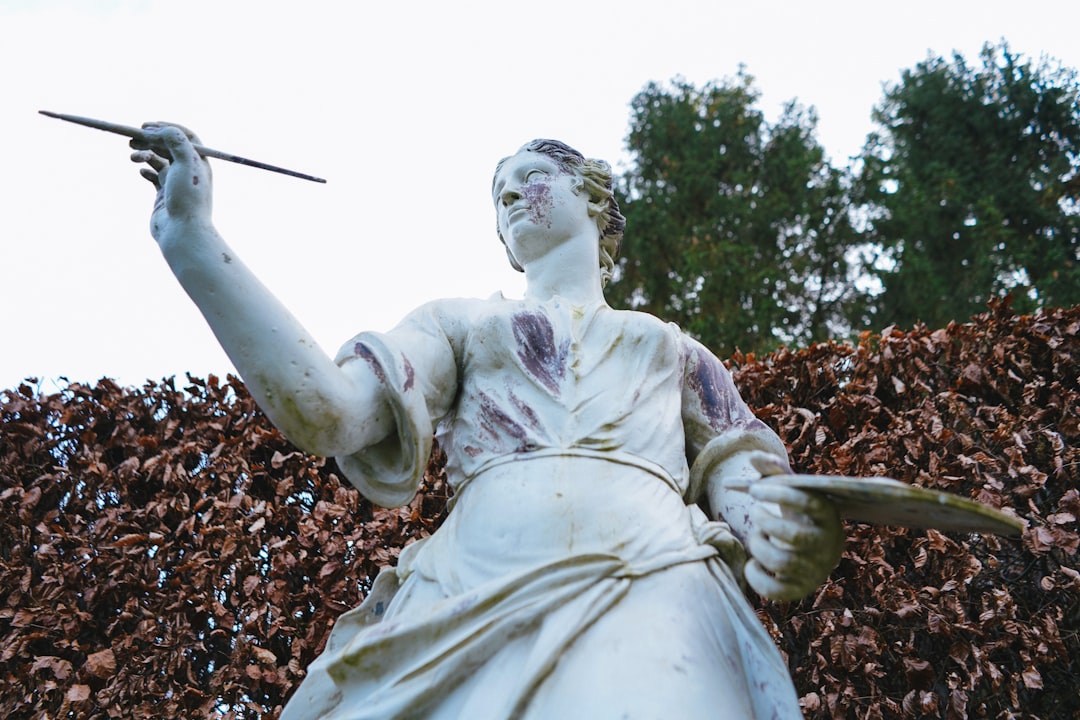 white concrete statue of a man holding a stick