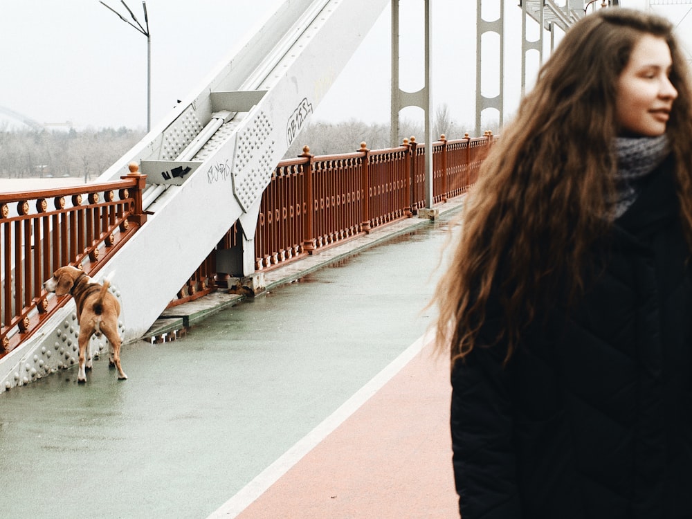 a woman walking her dog across a bridge
