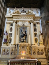 A close-up of a dark blue altar adorned with delicate golden details and a lit candle.