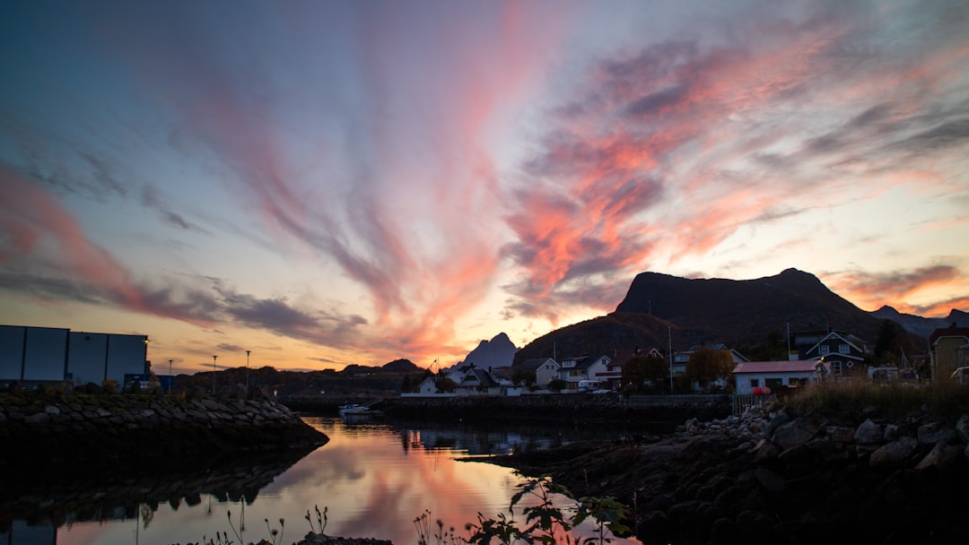 body of water near mountain during sunset