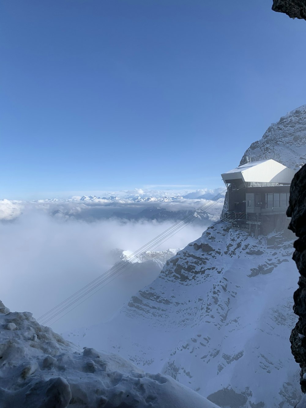 white building on snow covered mountain under blue sky during daytime